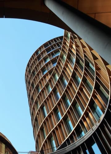 A modern building with a unique curved wooden structure, blending architectural elegance with natural elements.