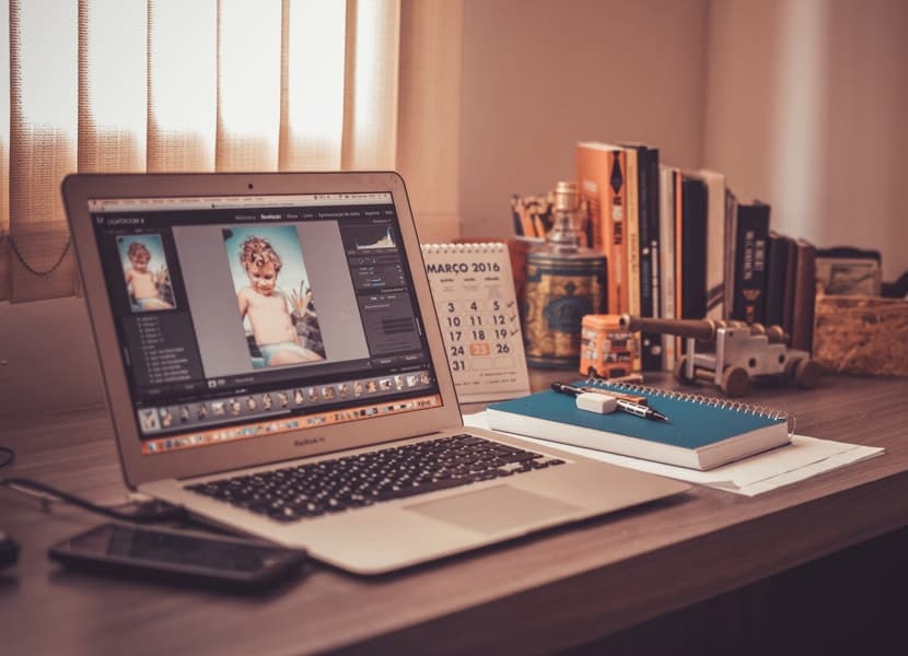 A laptop on a desk with a photo of a woman.