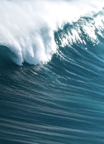 A powerful wave crashing on the ocean, creating a dramatic splash of water and foam.