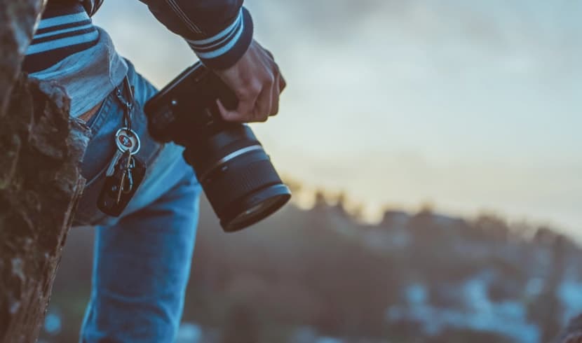 A photographer on a rock, holding a camera to capture the moment.