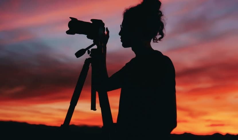 A photographer on a rock, holding a camera to capture the moment.